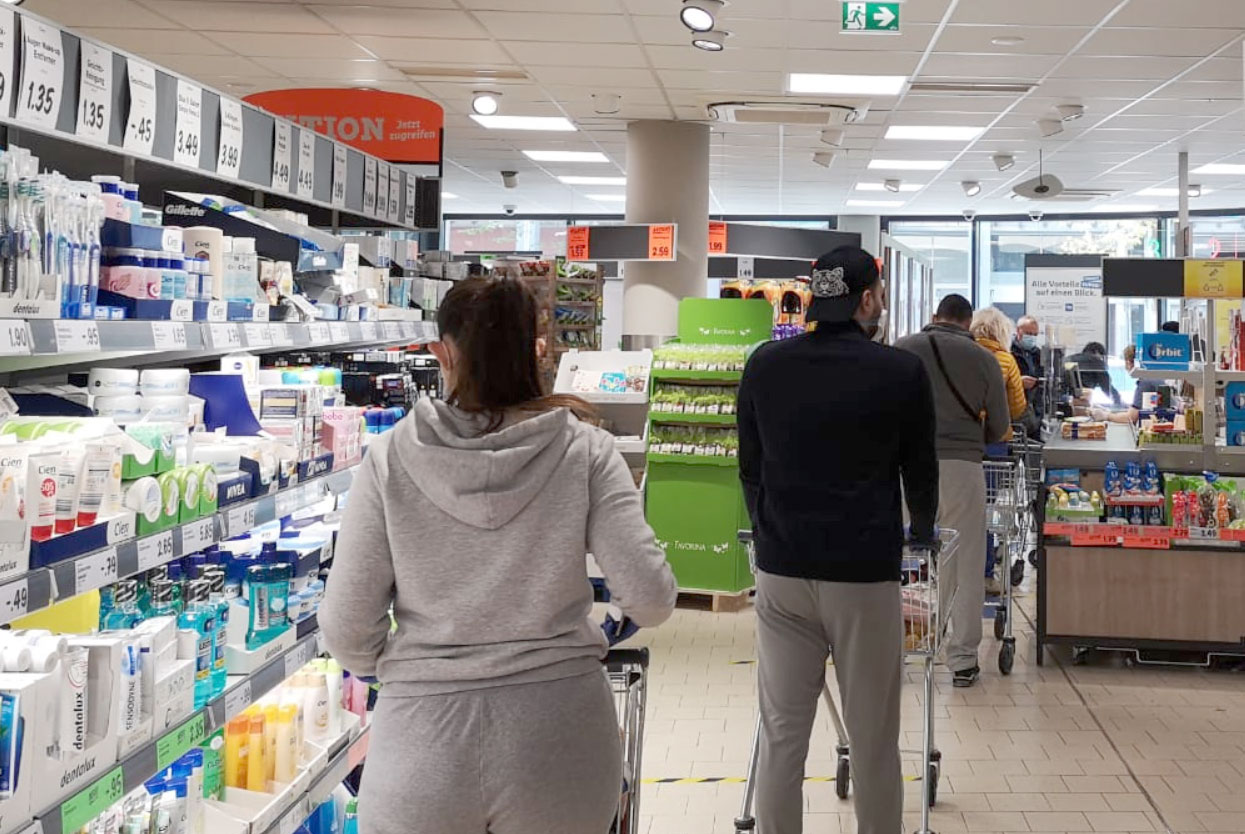 Gente en una cola en la caja del mercado con la distancia requerida por el gobierno.