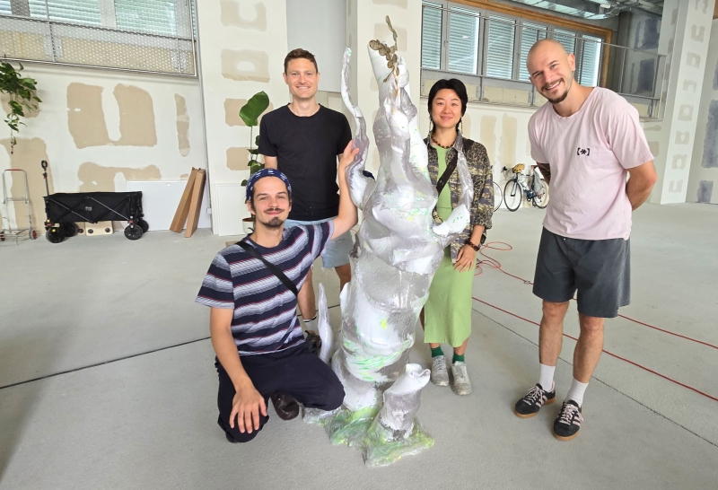 v.l.n.r.: Max Scheidl, Raphael Volkmer, die Künstlerin Mary Maggic und Julian Jankovic vor einem Baumstamm aus recyceltem Plastik, der derzeit „wächst“. 