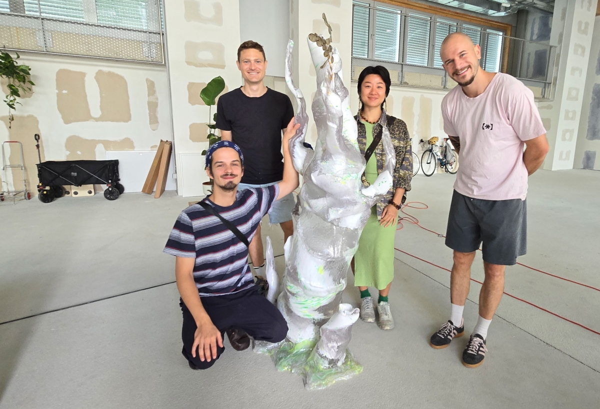 v.l.n.r.: Max Scheidl, Raphael Volkmer, die Künstlerin Mary Maggic und Julian Jankovic vor einem Baumstamm aus recyceltem Plastik, der derzeit „wächst“. 